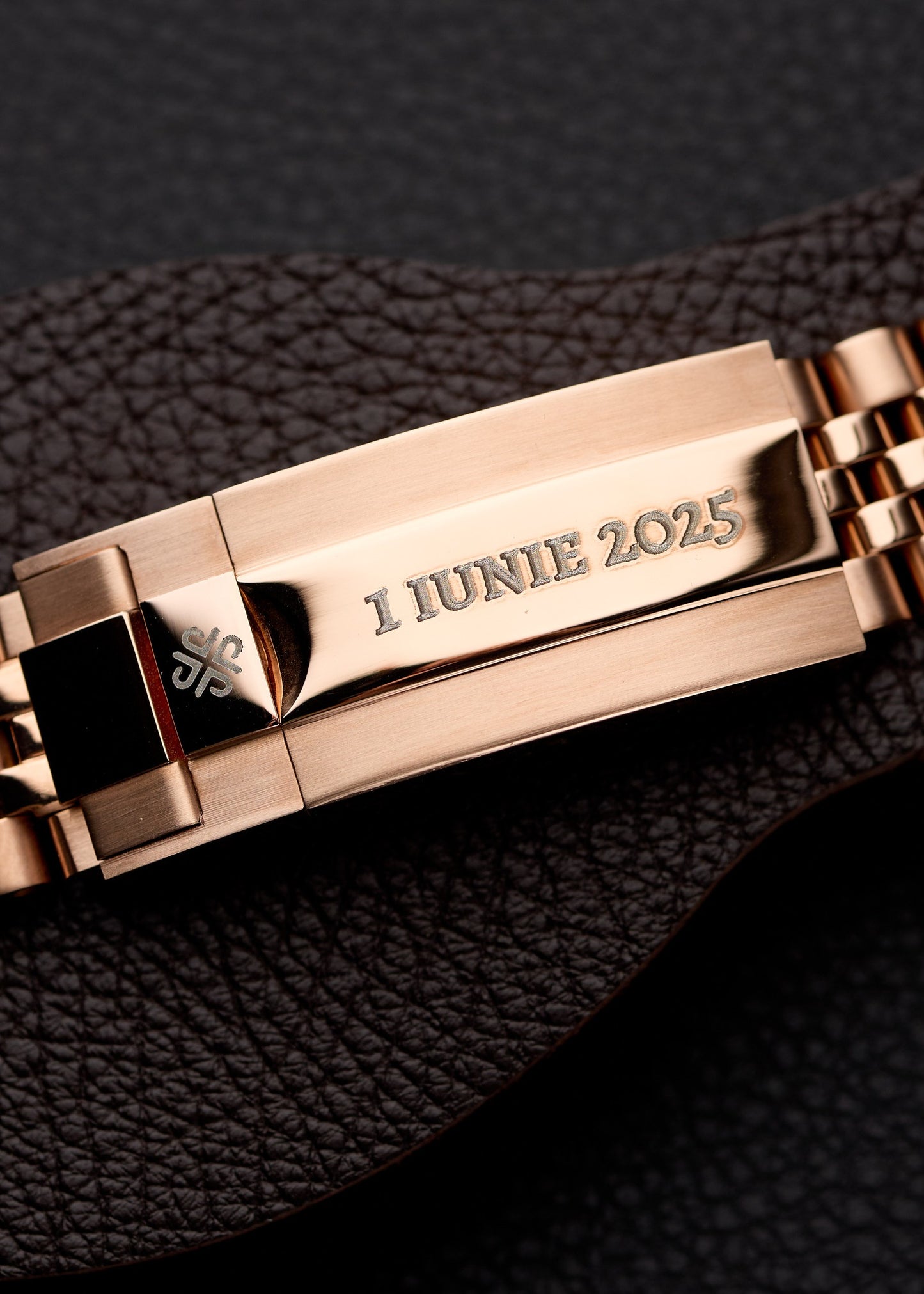 The LadyJust, detaliu al cataramei din aur roz gravate personalizat cu textul 1 IUNIE 2025, pe piele neagră.