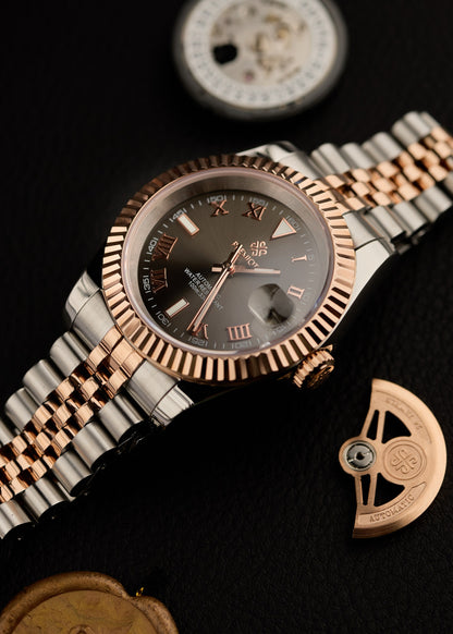 The Just Date, ceas automatic personalizat cu cadran maro, aur roz, langa piese de mecanism si unealta de ceasornicar.