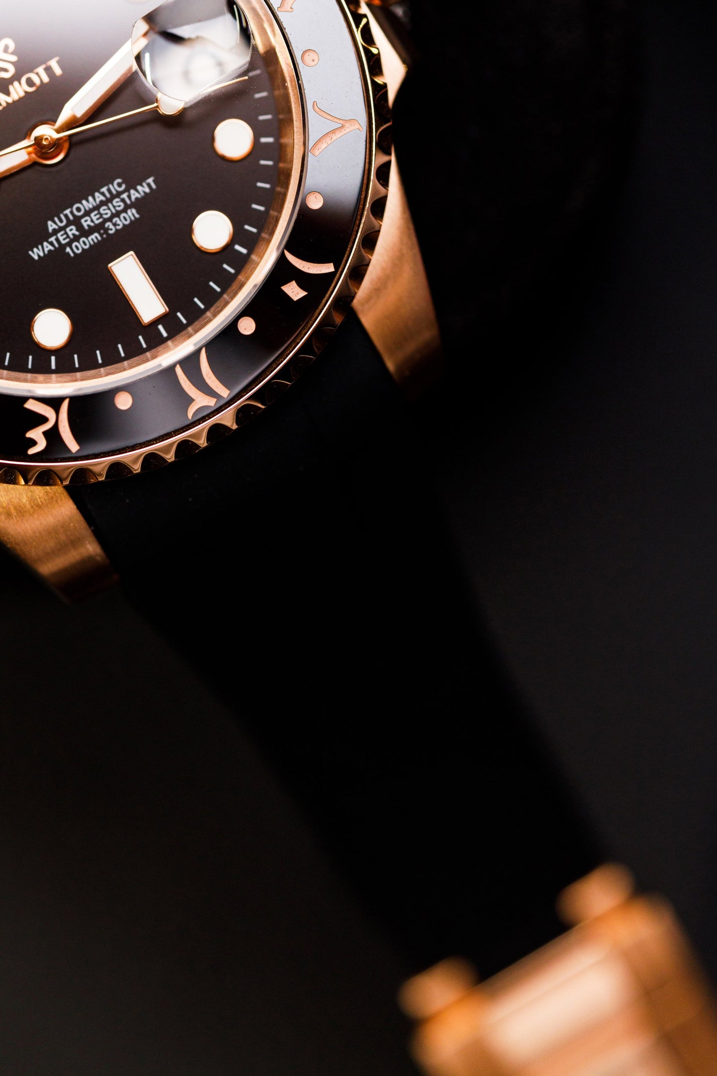 Detaliu cadran și bezel aurii The Mariner, prim-plan diagonal cu curea din cauciuc negru