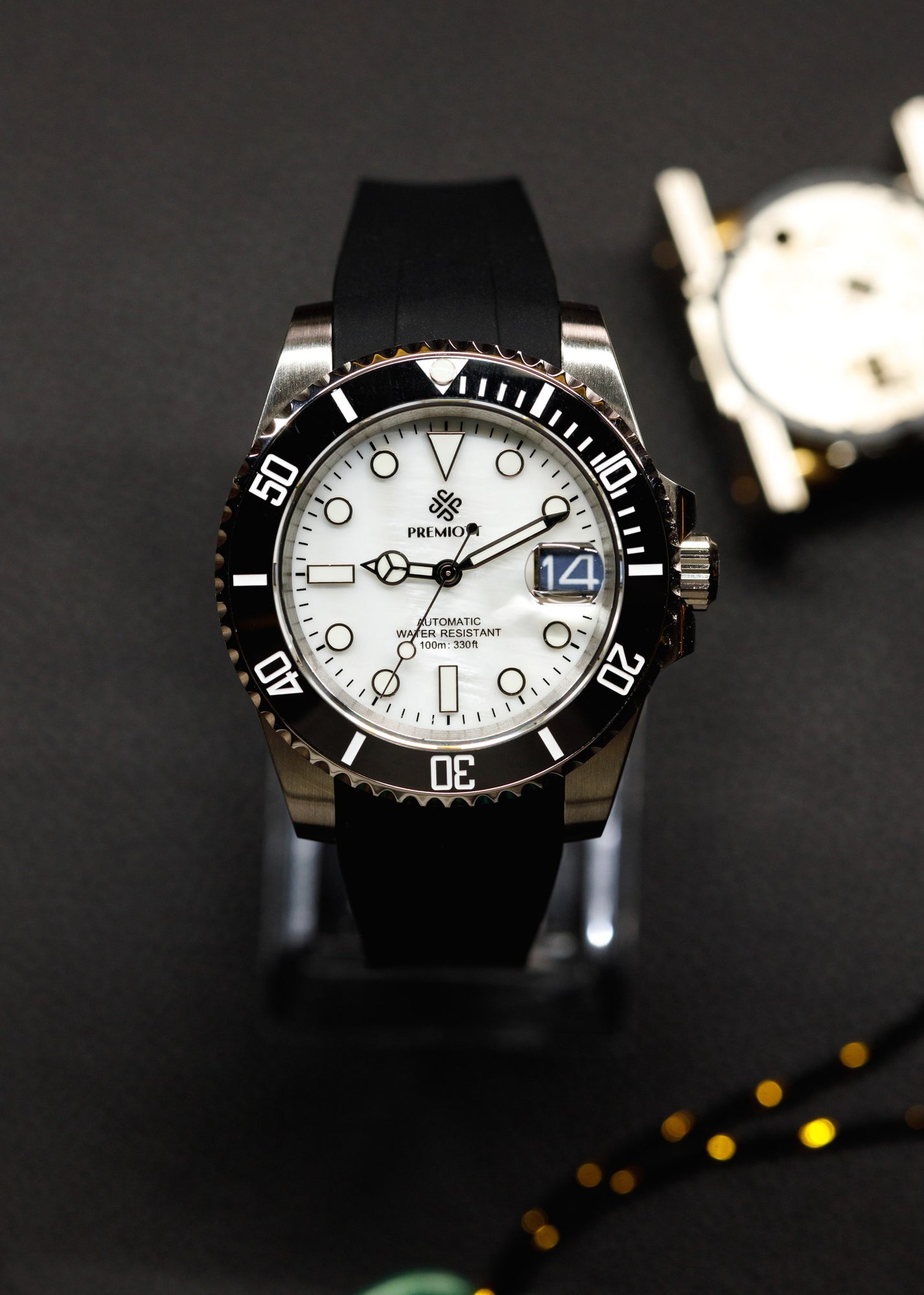 The Mariner cu cadran alb, bezel ceramic negru și curea din cauciuc negru, pe un suport pentru ceasuri
