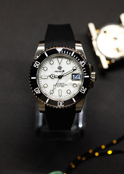 The Mariner cu cadran alb, bezel ceramic negru și curea din cauciuc negru, pe un suport pentru ceasuri